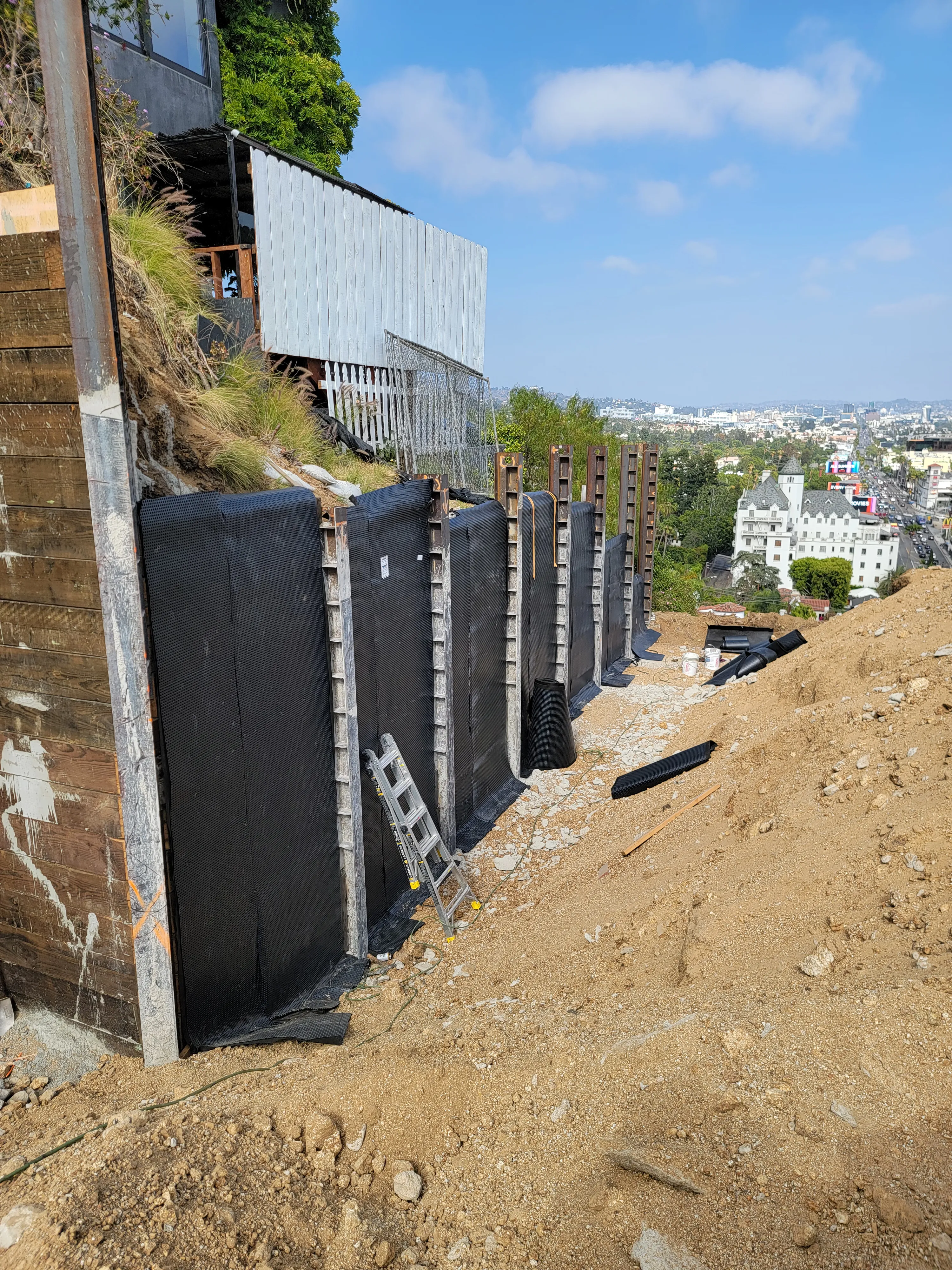 A concrete foundation wall being treated with a professional waterproofing barrier