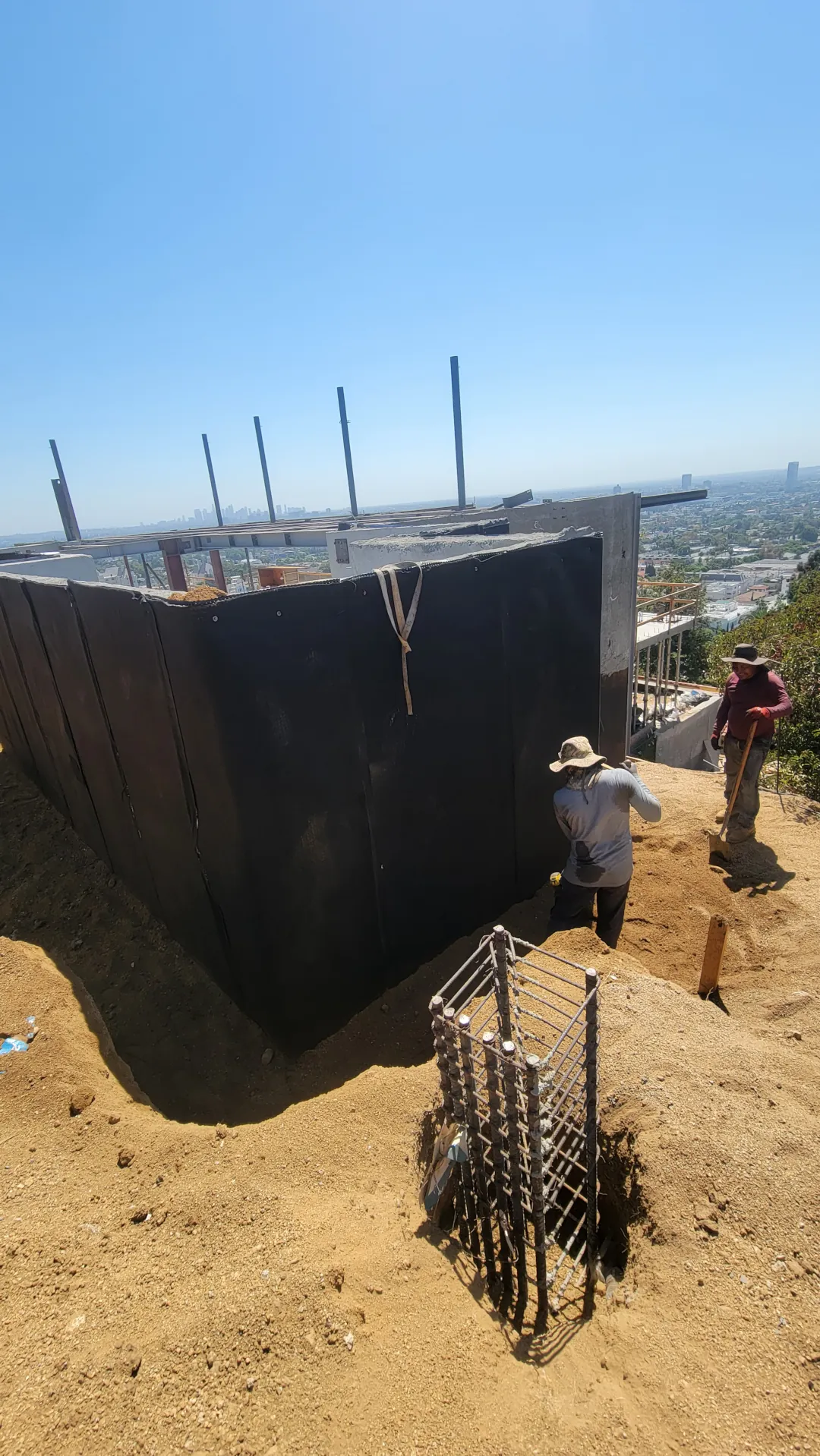 A concrete foundation wall being treated with a professional waterproofing barrier