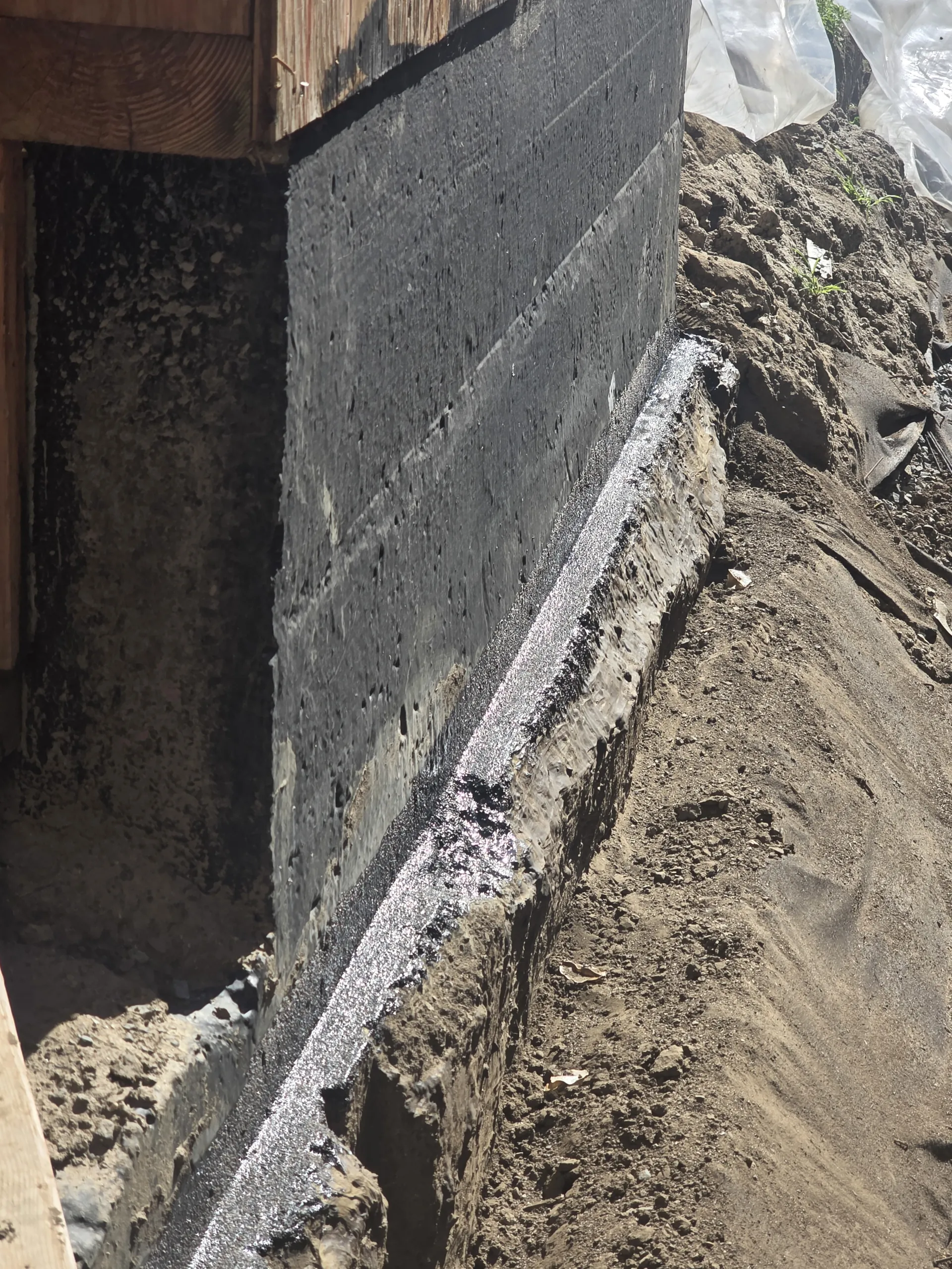 Below-grade foundation wall with professional waterproofing membrane installed