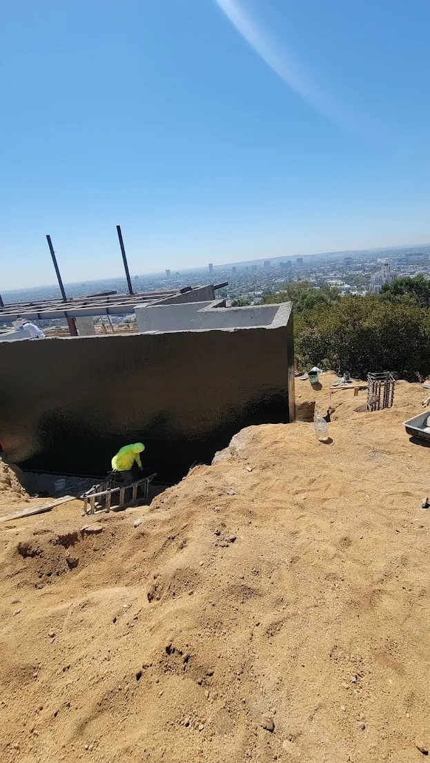 Specialty crew installing dimpled drainage protection board over fluid-applied subterranean foundation waterproofing membrane.
