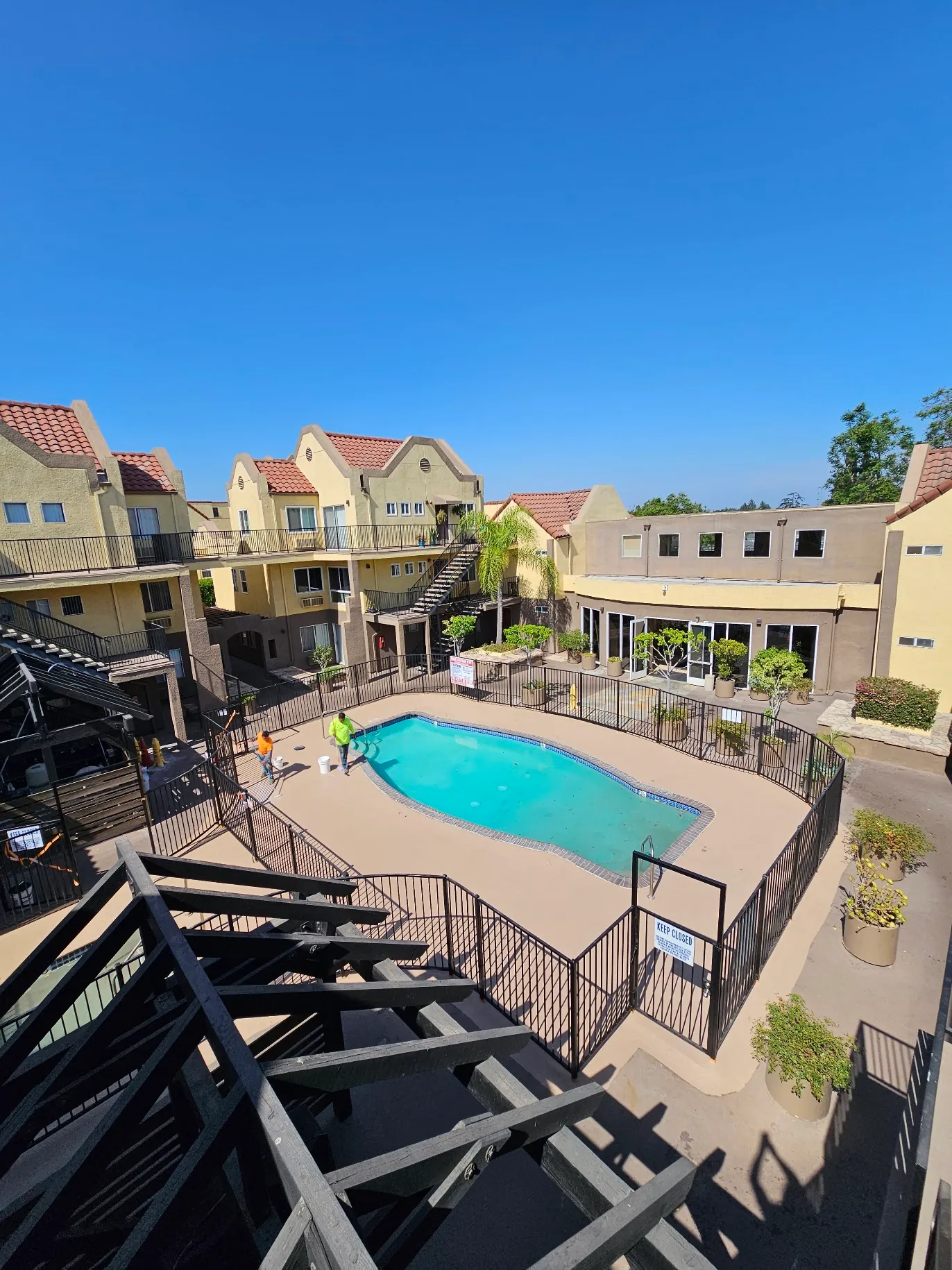 Waterproofing crew applying heavy-duty non-slip deck coating on an apartment walkway in Orange County.